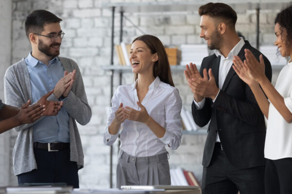 Work people standing in a room clapping and congratulating someone